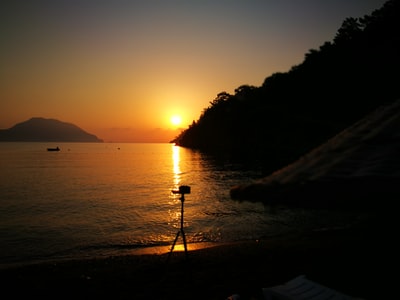 日落时一个人站在海边岩石上的剪影
